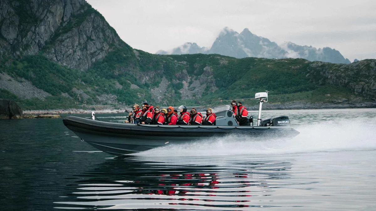 RIB boat speeding past steep mountain walls in Raftsundet on a Lofoten Islands Trollfjord tour from Svolvær